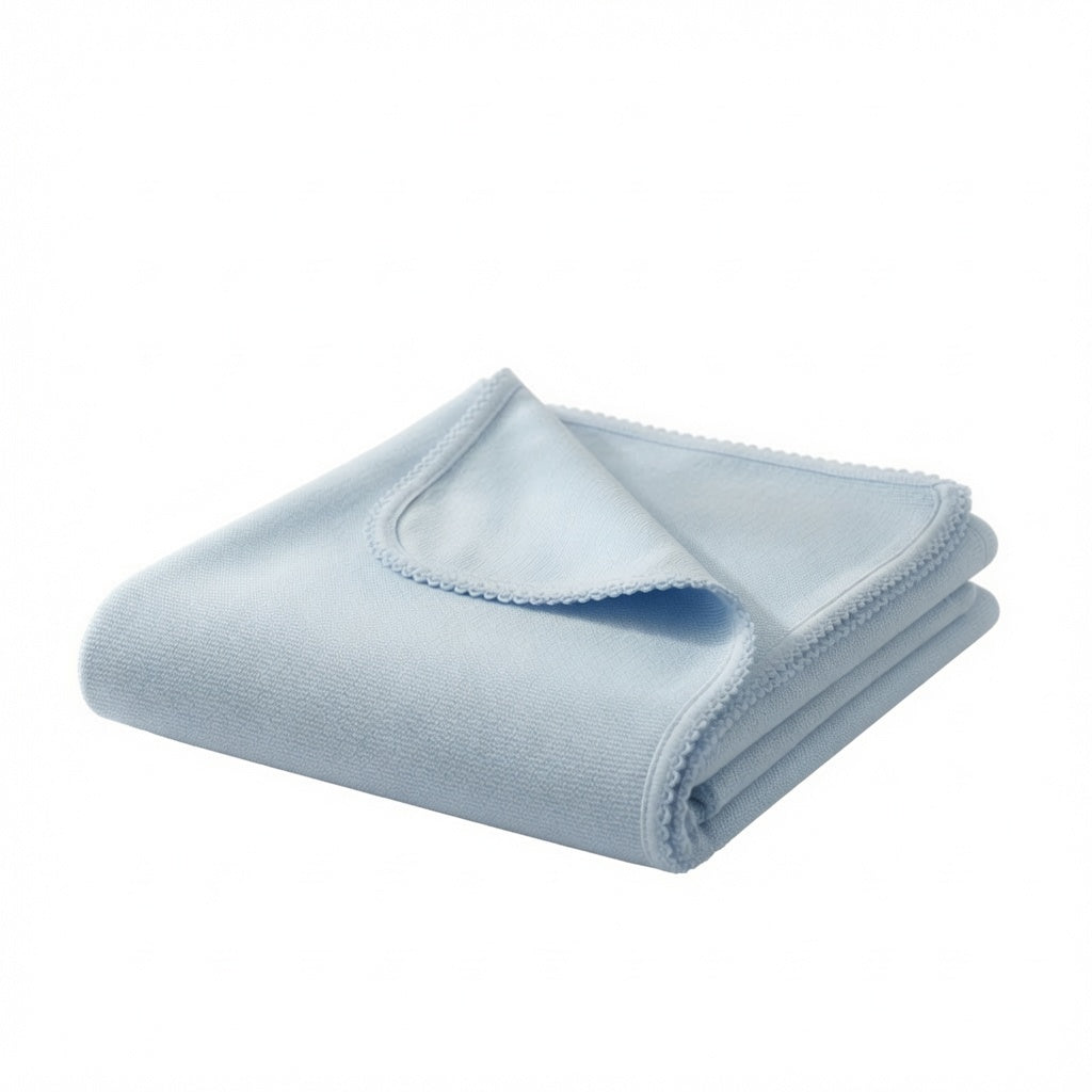A light blue knitted blanket, folded neatly with one corner folded over to show the fine fabric texture, set against a plain white background.