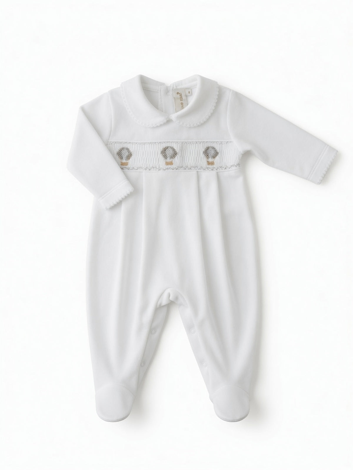 A white long-sleeve baby footie with a smocked chest panel featuring three small hot air balloon hand embroidery motifs, displayed flat against a white background from the front side.