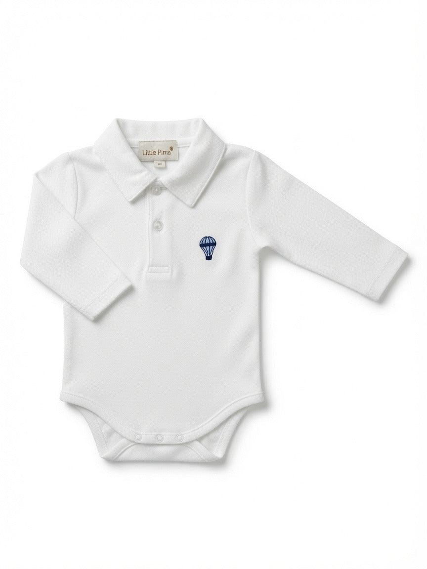 A white long-sleeve baby polo bodysuit with a small blue hot air balloon embroidered on the left chest, made from Peruvian pima cotton.