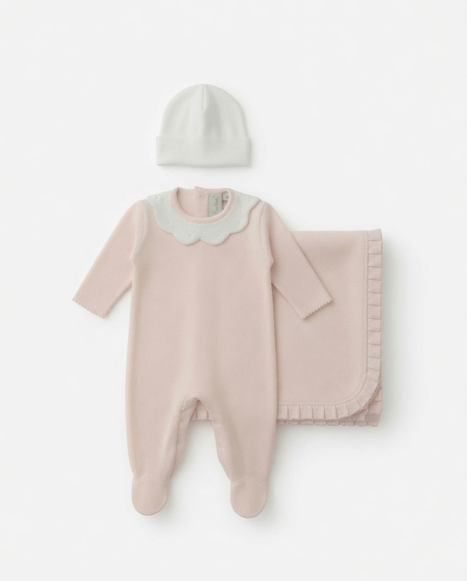A baby clothing set featuring a soft pink footies with a white collar, a matching light pink blanket, and a small white beanie, laid out on a white background.