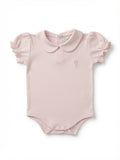 A light pink baby bodysuit with a Peter Pan collar, short ruffled sleeves, and a small embroidered hot air balloon logo on the left chest made from Peruvian Pima Cotton.