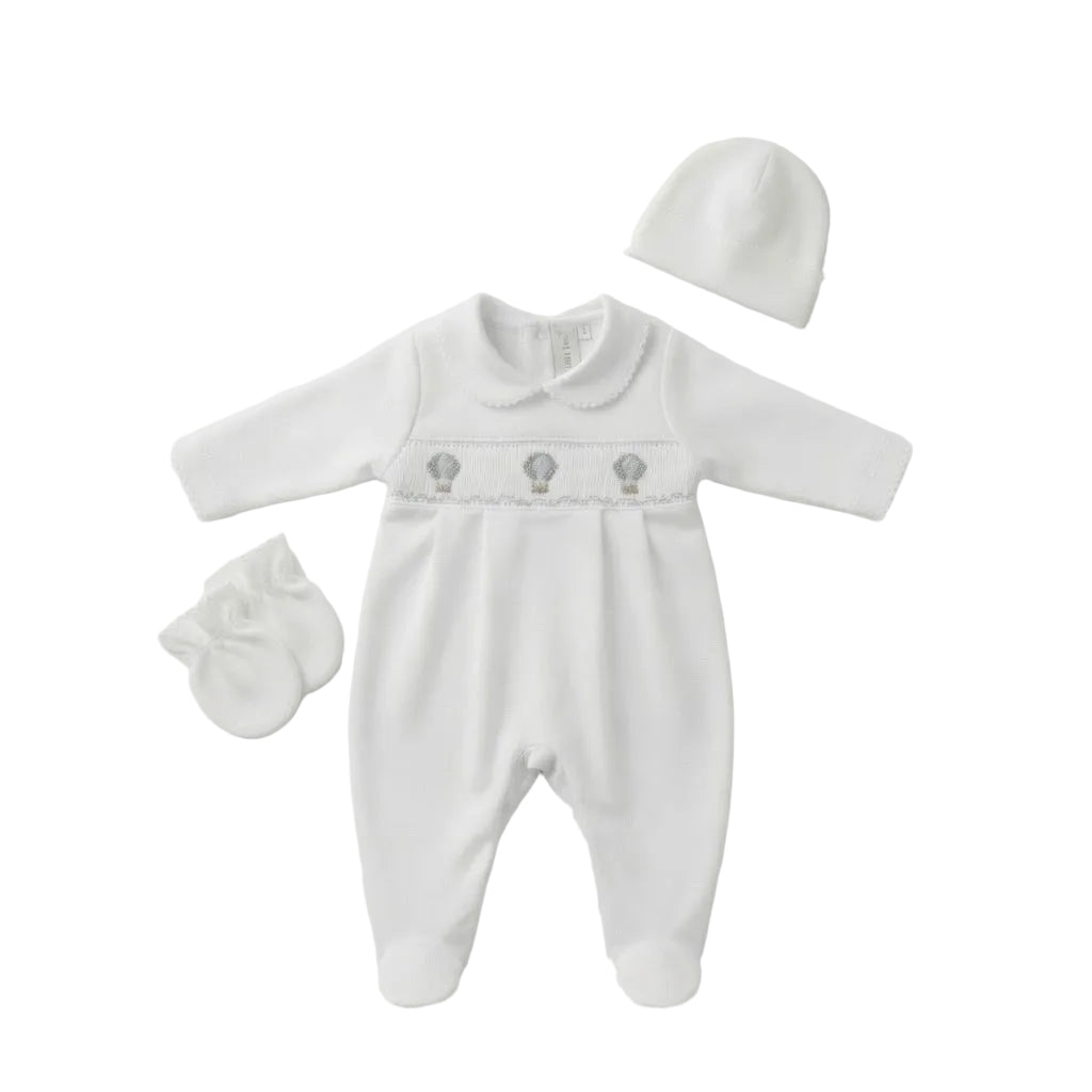 A white baby footie set with long sleeves, a Peter Pan collar, three small hot air balloon hand-embroidered motifs across the chest, a matching hat, and a pair of mittens, laid out on a clean white background.