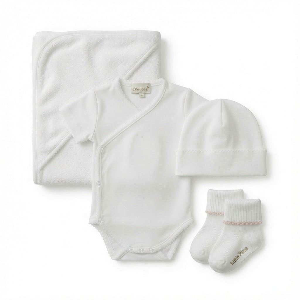 A baby towel set laid out on a white background, including a folded white hooded towel, a white short-sleeve bodysuit, a white beanie hat, and a pair of white socks.